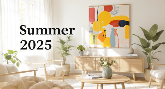Bright modern living room interior with summer decor, featuring a large abstract colorful poster on the wall, light wooden furniture, indoor plants, and soft natural lighting. Overlay text reads “Summer 2025” in bold black font.