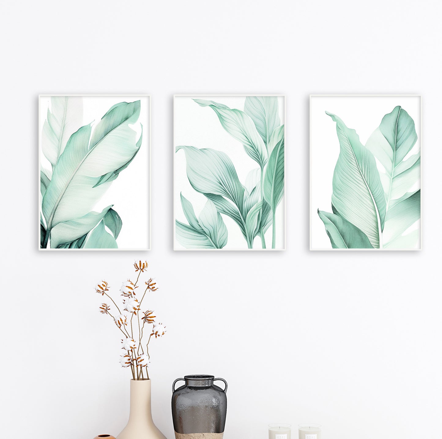 A trio of botanical posters with green leaves displayed in wooden frames, arranged side by side on a white wall.