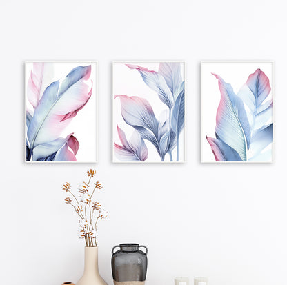 Blush and blue botanical wall art trio hanging on clean white wall in minimalist wood frames.

