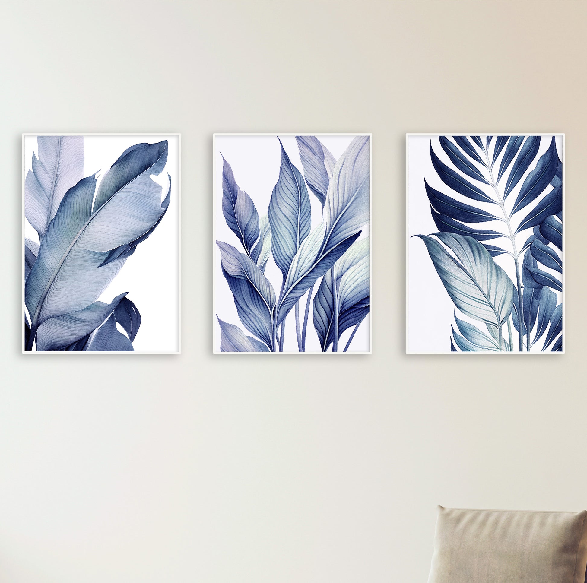 Comfortable white armchair placed beneath three vertical leaf posters, creating a cozy and stylish reading nook.

