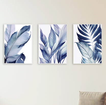 Comfortable white armchair placed beneath three vertical leaf posters, creating a cozy and stylish reading nook.

